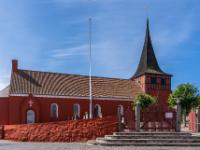 Rote Svaneke Kirche mit dunklem, spitzen Turm - Svaneke